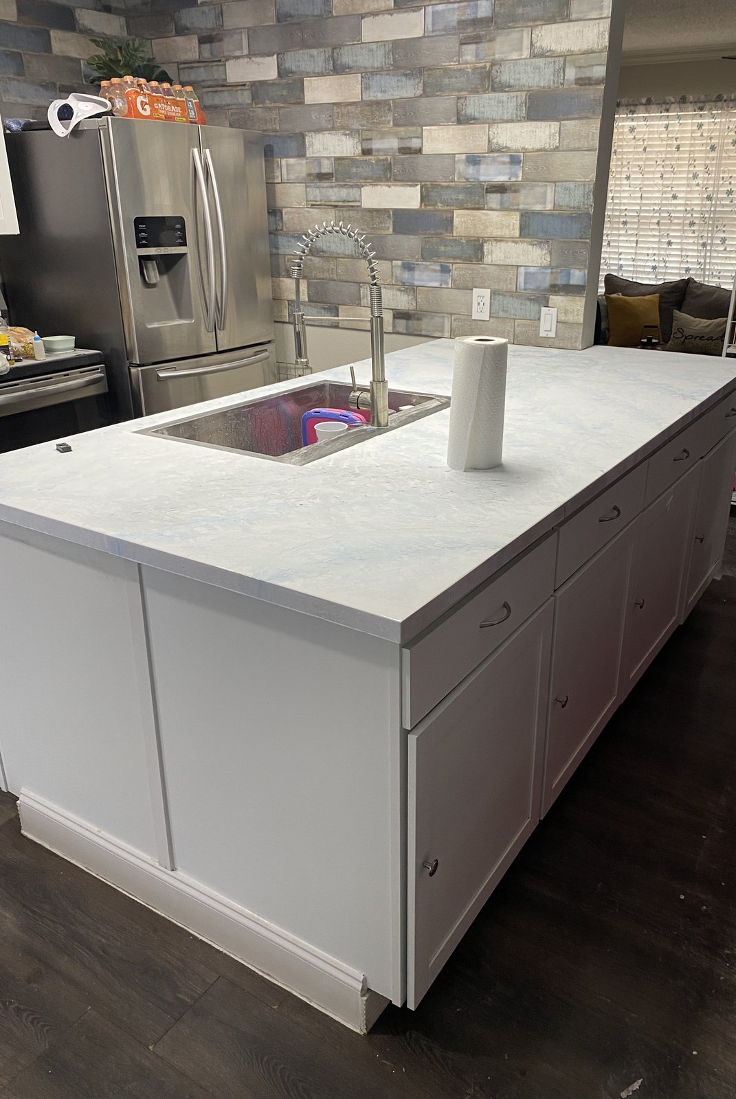 Kitchen island with a matte white epoxy countertop with soft blue and silver metallic highlights, undermount stainless sink, and white cabinets